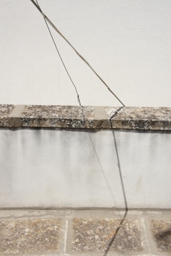 Image of an Metalstring ending behinde a stone wall